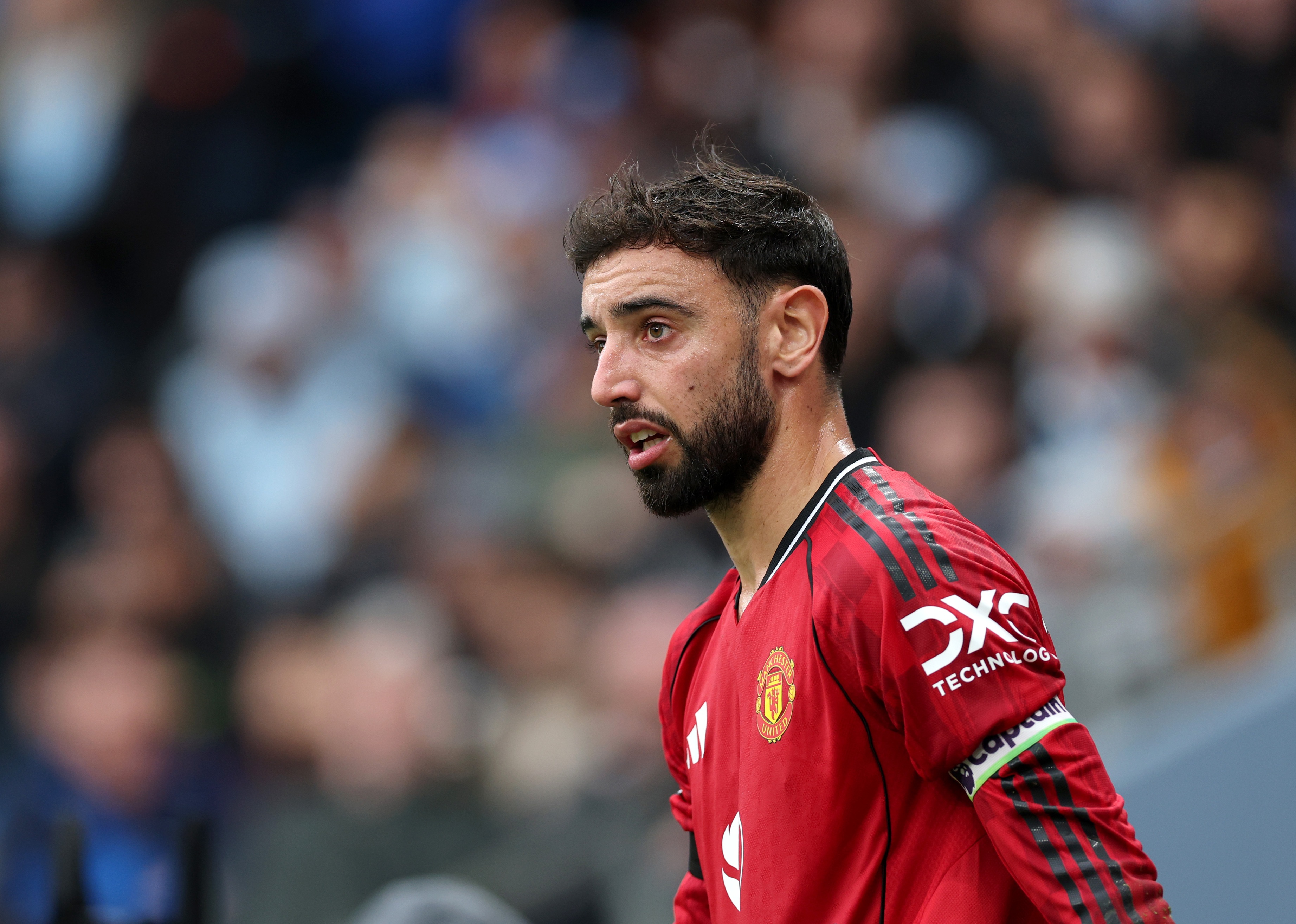 Bruno Fernandes looks on at the Etihad Stadium with fans in the background.