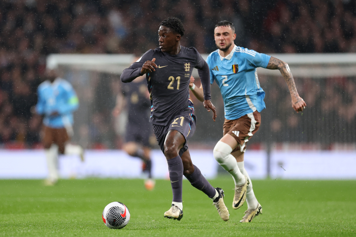 Kobbie Mainoo of England runs with the ball whilst under pressure from Zeno Debast of Belgium