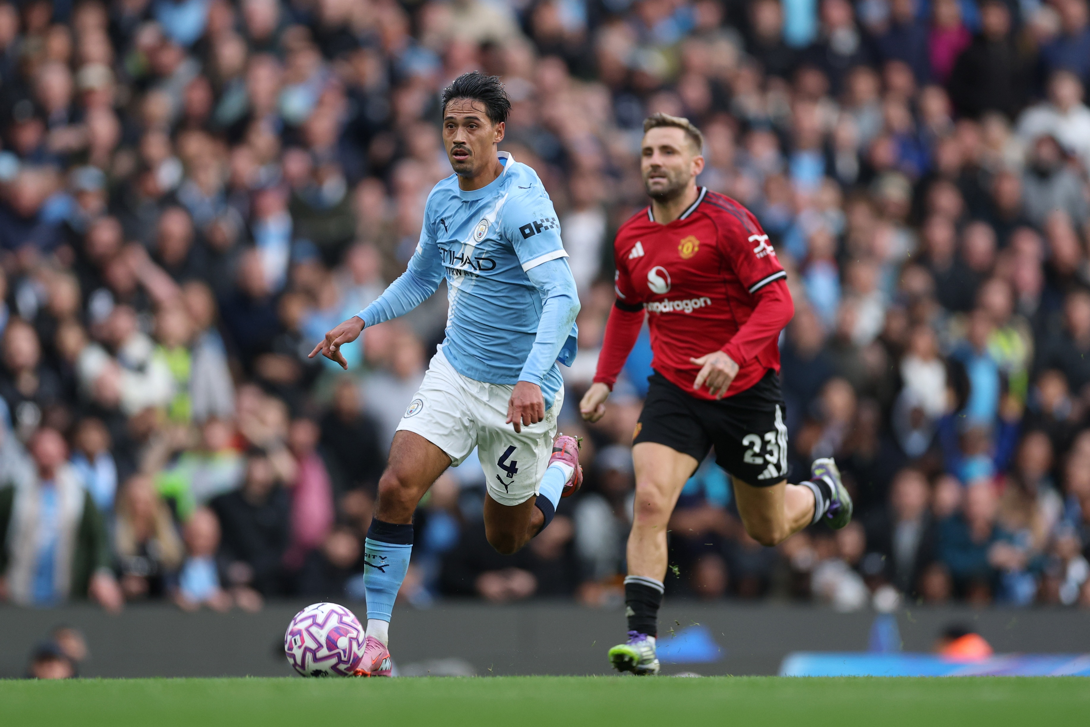 Luke Shaw chases behind as Tijjani Reijnders runs with the ball.